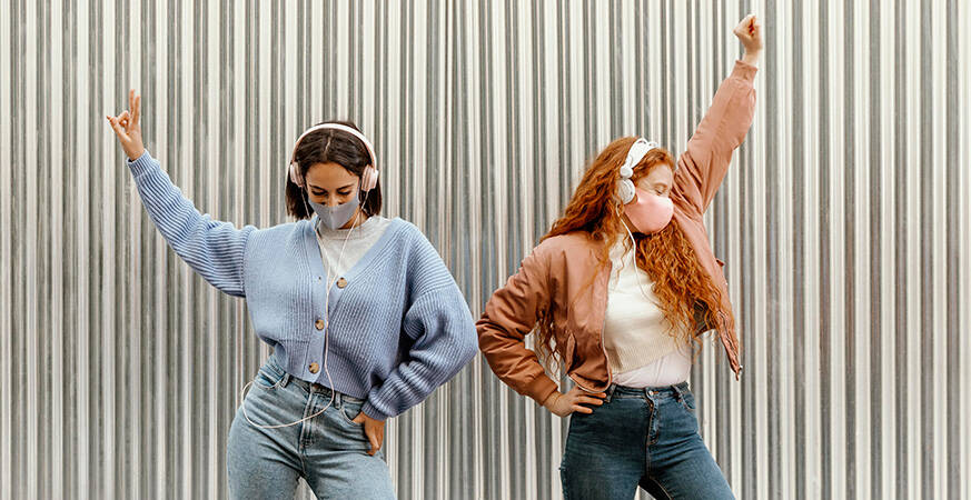 two women wearing headphones and dancing with their hands raised