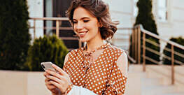 lady with clear skin checking her phone while walking outside